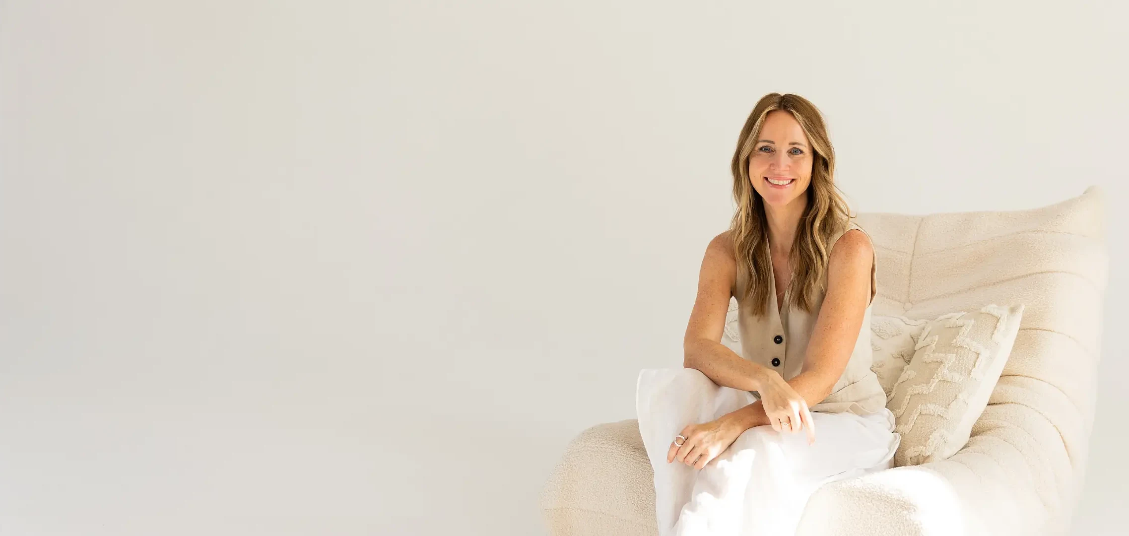 Carina Reichert, Visual Brand Partnerin, sitzt lächelnd in einem hellen Sessel